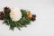 Christmas pine cone candle and tree in rustic christmas wreath on white wood. Small pine tree and modern wreath from white cedar