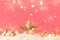 Christmas pink background with golden star. New Year`s decor. Christmas balls in smowdrifts and golden bokeh lights