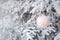 Christmas pink ball hangs on snow-covered spruce branch in the forest. Selective focus. Fairytale mood. Concept of Christmas and