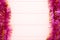 Christmas pink tinsel on pink wooden background