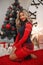 Christmas portrait of attractive woman with curly hairstyle. Beutiful blond girl with long hair style wears in warm red knit