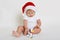 Christmas portrait of charming little baby boy, wearing santa hat, playing with little cute plastic dog toy, infant studying new