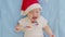 Christmas portrait of cute crying little newborn baby girl, wearing santa hat.