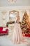 Christmas portrait of a girl in a glittering festive dress on the background of Christmas decor in elegant interior. A woman