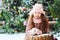 Christmas portrait of happy kid girl playing outdoor in snowy winter day, fir trees decorated for New Year holidays