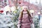 christmas portrait of happy kid girl playing outdoor in snowy winter day, fir trees decorated for New Year holidays