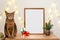 Christmas poster frame mock up. Abyssinian cat sitting green fir branches gift boxes lights garland. Wooden empty frame