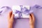Christmas present stylish gift box in kids hands on lilac background. Creative Flat layout top view composition, valentine,