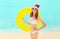 Christmas pretty smiling woman in red santa hat with circle inflatable on beach over sea