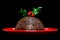 Christmas pudding with holly isolated on black