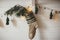 Christmas rustic stocking with fir branch and stylish garland with bells and trees on white wooden wall with christmas lights.