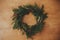 Christmas rustic wreath flat lay. Creative rural christmas wreath with fir branches, berries, pine cones and herbs on wooden table