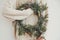 Christmas rustic wreath. Hipster girl in stylish white sweater holding rural christmas wreath with fir branches, berries, pine