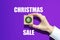 Christmas sale. Power button, on a wooden block in a woman`s hand. Purple background. Festive concept of starting sales. Business