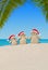 Christmas sandy Snowmen family in Santa hats at palm beach