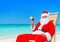 Christmas Santa Claus with cocktail on sunlounger at tropical be