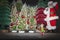 Christmas Santa figure with elf and list of names by decorative Christmas trees on shelf