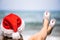 Christmas sea holiday. Woman in santa claus hat and slippers relaxing on paradise beach island. New year.