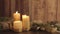 Christmas setting with moving flames of three lit candles, pine boughs, natural pine cones, golden satin and white organza ribbons
