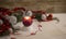 Christmas setting: a red lit candle with cross screen effect on foreground surrounded by pine branches, red baubles, red and white