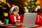 Christmas shopping concept. Gifts service. Santa little helper. Smart toddler surfing internet. Little boy santa hat and