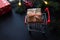 Christmas shopping concept. Grocery cart and present on festive background. Winter holidays, discounts and season sales. Close-up