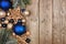Christmas side border with dark blue and gold ornaments and tree branches, top view on a wood background