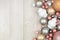 Christmas side border of dusty rose, dark silver and white ornaments, top view on a gray wood background