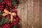 Christmas side border with red and black checked buffalo plaid ribbon, burlap and branches, overhead view on a wood background