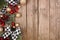 Christmas side border with white and black checked buffalo plaid ribbon, decorations and branches, overhead on a rustic wood backg