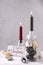 Christmas sign,  glass candleholders with gold, black, silver decorative cones and grey and red candles on grey textured backgroun