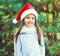 Christmas smiling child little girl in santa red hat over tree