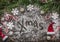 Christmas snowy background with the words x-mas Christmas candy, hat and pine branches and pine cone on wooden rustic background
