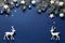 Christmas snowy border of shiny balls, stars and deer, evergreen branches on classic blue background
