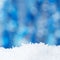 Christmas snowy holiday background with snow and shiny blur backdrop. White snow with blue glitter bokeh. Decor for the New Year`