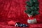 Christmas stocking spilling out coal candy, for bad boys and girls, with a burlap ball artificial tree, on a red background