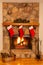 Christmas stockings adorn a beautiful stone fireplace with a glowing fire