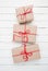 Christmas style rustic brown paper package tied up with strings. White wood background.