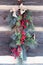 Christmas swag with pine, twigs, red berries, and burlap bow on wood wall