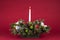 Christmas Table Arrangement or Centerpiece with flowers, evergreen branches and White Lit Candle