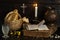 A Christmas table, bread in a basket and a glass of water bring a prayer book to a dark wooden table. Cross in the background
