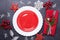 Christmas table place setting with empty red plate, cutlery with festive decorations star bow ball on stone background