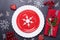 Christmas table place setting with empty red plate, cutlery with festive decorations star bow ball on stone background