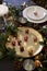 Christmas table setting with baubles on golden plate, bauble name card holder arranged on plate and green and red decorations, clo