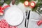 Christmas table setting with candles, champagne, gift box and fir tree branch covered by snow on stone background. Top view with