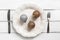 Christmas table setting. Christmas-tree balls on a white plate, knife, fork. White wooden rustic table. Top view, flat lay. The