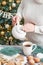 Christmas table setting. Woman pouring tea. Treats and food. Tea set and sweets on background of Christmas tree. Christmastime