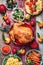 Christmas or Thanksgiving whole roasted chicken, rice, pumpkin, corn, honey, nuts, vegetable salads over wooden background. Top