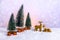 Christmas theme with miniature reindeers, Christmas trees and presents on light purple snowy background