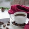 Christmas time concept: a white cup of coffee stands on a white wooden table next to a white open book and colorful candy against